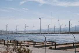 Panneaux solaires sur une surface sablonneuse. Derrière les éoliennes..