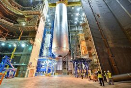 Un énorme réservoir d'hydrogène cylindrique est déplacé à travers un hall industriel à l'aide d'une grue.