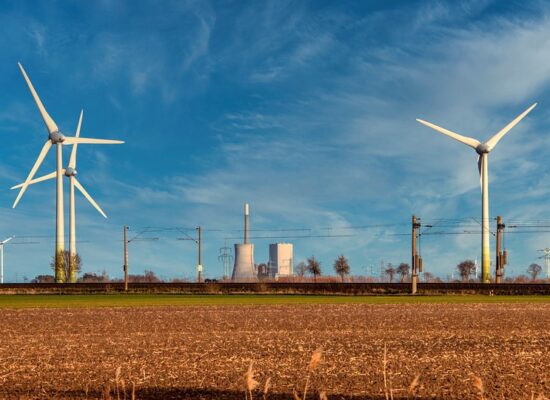 Windräder auf Feld vor Industrieanlagen