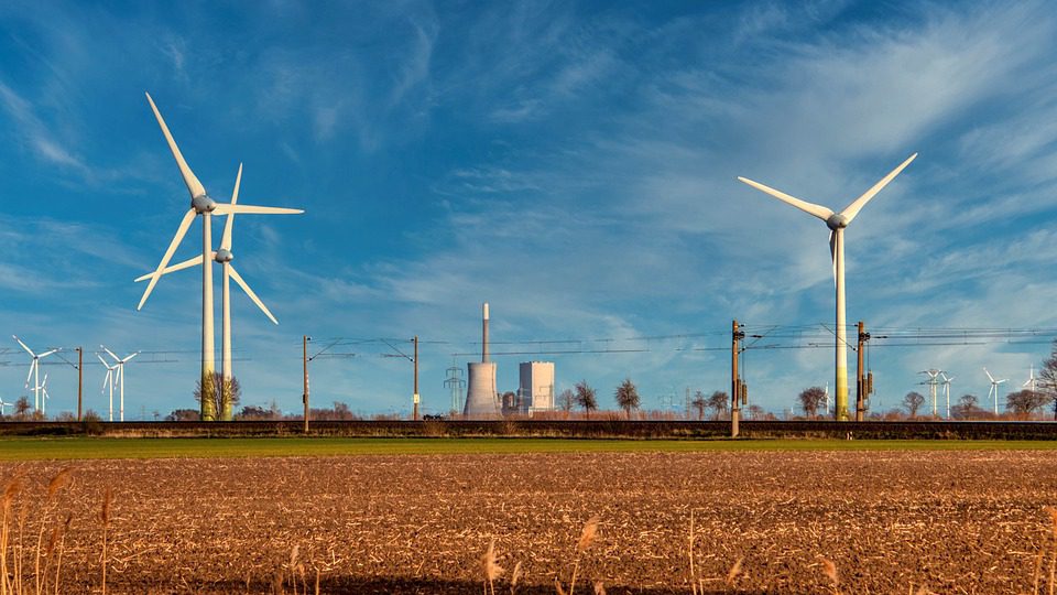 Windräder auf Feld vor Industrieanlagen