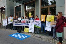 Des personnes se tiennent debout devant le bâtiment de l’association de lobbying «Zukunft Gas» avec des panneaux de protestation