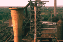 Une usine de fer devant un paysage verdoyant.
